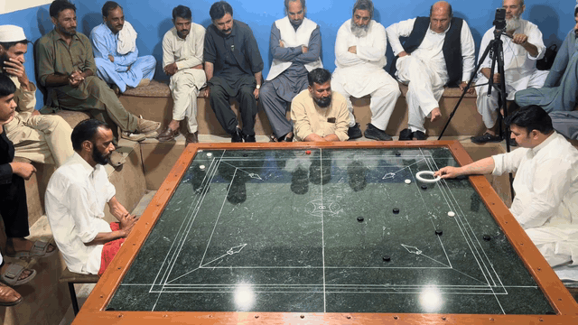 Pakistani carrom shot 1: the striker and pieces glide across the marble board.