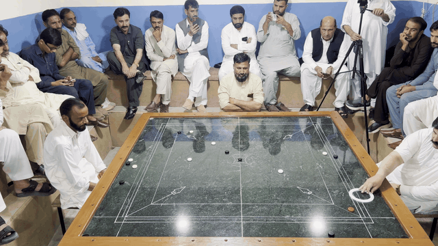Pakistani carrom shot 4: the striker and pieces glide across the marble board.