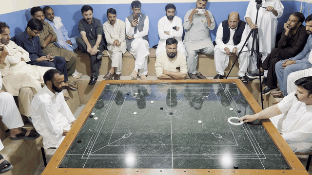 Pakistani carrom shot 5: the striker and pieces glide across the marble board.