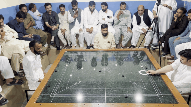 Pakistani carrom shot 2: the striker and pieces glide across the marble board.
