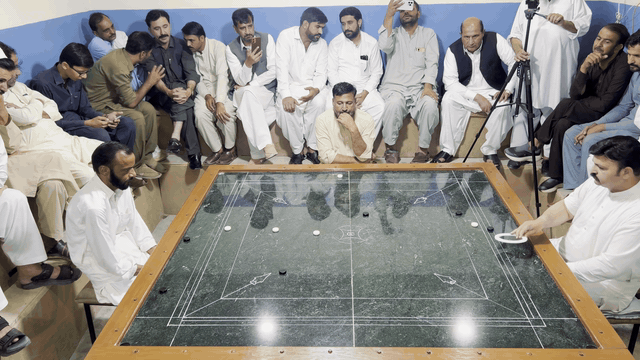 Pakistani carrom shot 6: the striker and pieces glide across the marble board.