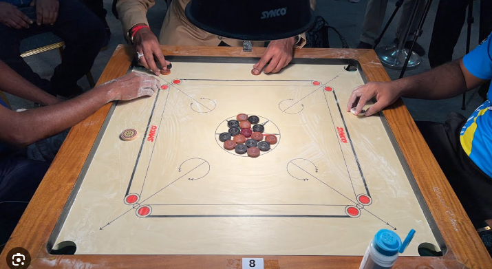 Players gathered around a traditional wooden carrom board.